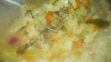 spoon mixes borscht with cabbage and meat, close-up.