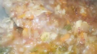 spoon stirs red borscht with meat, macro, a popular dish in Ukraine, Moldova and Russia.
