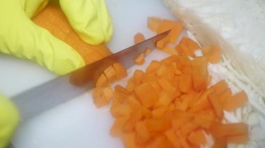  the chef's hand cuts carrots with a knife on a cutting board for cooking borscht.