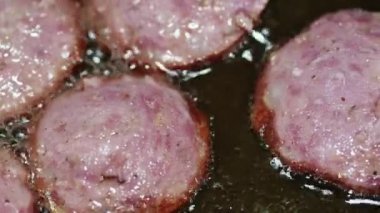 macro video of sliced sausages frying in sunflower oil in a frying pan