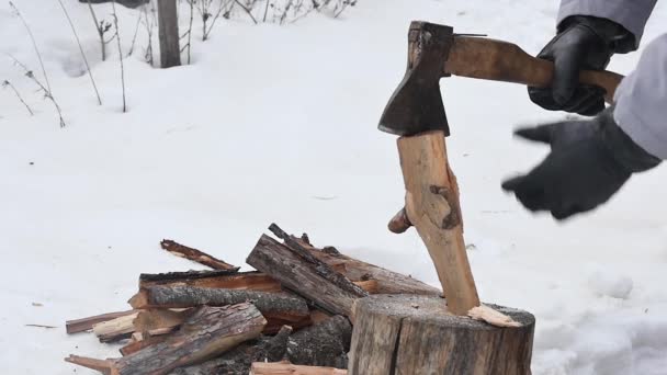 斧のついた黒い手袋の手は雪の庭で丸太を切ることができずゆっくりとした動き — ストック動画