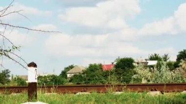  Doğu Avrupa 'daki bir köyün arka planına karşı eski demiryolu rayları üzerinde güzel beyaz bulutların hareketinin zamanaşımı