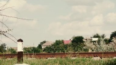 Güzel beyaz bulutların, eski demiryolu rayları üzerinden köyün arka planına doğru hareket etmesinin zaman aşımına uğraması.