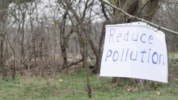 在春天森林的背景下 在树枝上贴上题词的纸可以减少塑料垃圾附近的污染 — 图库视频影像