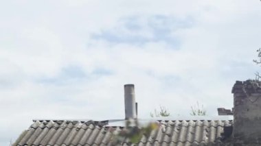  Beyaz bulutların bacalı eski bir çatı üzerindeki hareketlerinin zaman aşımına uğraması.