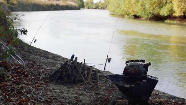 グリルのティーポット 釣り棒と秋の川の背景に対して — ストック動画