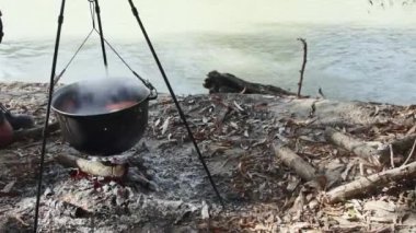 El ateşe odun ekler, kazanda balık çorbası pişirir doğada ateşte..