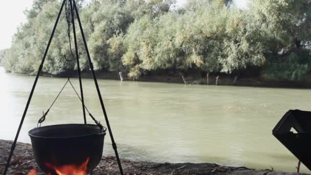 美しい川のほとりで 火の上に吊るされたカルドロンで料理する — ストック動画