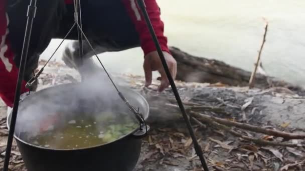 Cocinando Caldero Colgante Sobre Fuego Orilla Del Río Hombre Agrega — Vídeo de stock