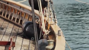 Sakin bir denizde, demirli bir yelkenli gemisinin sancak güvertesinde sallanıyor.