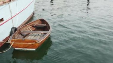 Tahta sallanan kahverengi tekne, geminin ahşap mavi tarafında bir iple bağlı.