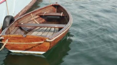 Geminin ahşap mavi tarafında bir iple bağlanmış ahşap sallanan tekne, yakın plan.