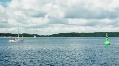 Ağaçlar, bulutlar ve yüzen bir yatla denizden sahile manzara