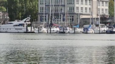  3 Eylül 2023. Limanda park etmiş yatlar ve kıyı boyunca koşan bir grup sporcu var.