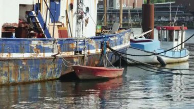 Flensburg, Almanya - 26 Temmuz 2023. Limandaki paslı bir geminin kenarına bağlanmış kırmızı bir tekne..
