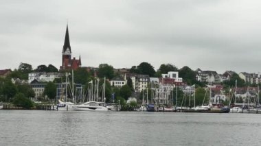 Flensburg, Almanya - 29 Temmuz 2023 Bir kilise ve bina ile demirli yatların arka planına karşı