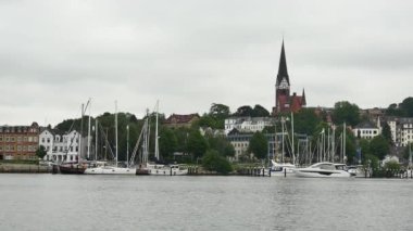 Flensburg, Almanya - 29 Temmuz 2023 Yaz Sahili Kiliseli ve binalı demirli yatlar