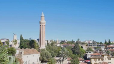 A beautiful, bright day view of the historical old town district of Kaleii, featuring the prominent Alaaddin Mosque Minaret (Yivliminare) rising from the urban landscape.