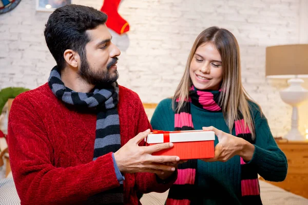 Young man giving presents for surprise girlfriend in celebration Christmas together at home, boyfriend giving gift woman with excited, event and festive x-mas, xmas and new year or holiday concept.