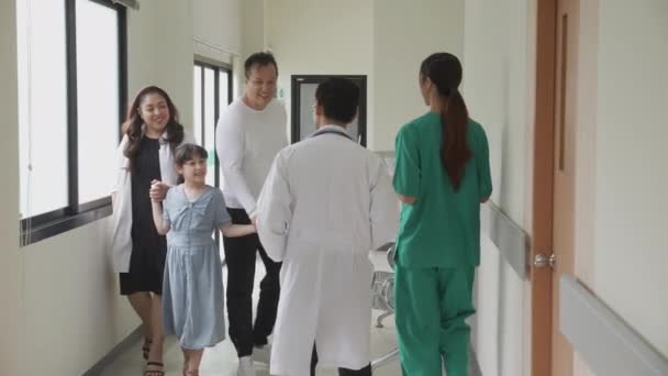 Lekarz Asystent Lub Pielęgniarka Spacerujących Korytarzem Powitanie Rodziny Pacjenta Dyskusji — Wideo stockowe