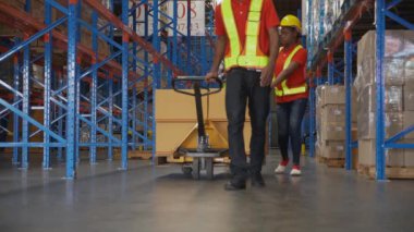 Delikanlı ve kadın, fabrikadaki depoda nakliye ve dağıtım için kargo taşıyıp taşıyorlar. Depoda çalışan işçiler, nakliye ve sanayi, lojistik ve nakliye konsepti..