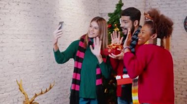 Genç arkadaşlar, Noel arifesinde, Noel arifesinde, Noel arifesinde, bayramında veya tatil konseptinde sosyal medyayı kullanan kadın ve erkek, heyecanlı ve akıllı telefonlardan keyif alarak görüntülü arama yaparlar..