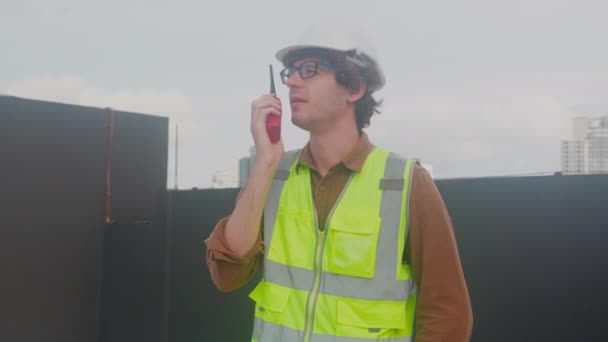 Young Caucasian Man Using Radio Conversation Inspecting While Building Tower — Video