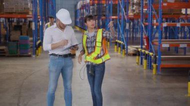 Genç bir kadın müdürle konuşurken fabrikadaki depodaki panoda imzalı belge, patronla raflardaki kargo dağıtımı, nakliye ve lojistik konsept hakkında çalışan tartışması..