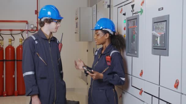 年轻的女工程师和男工程师在厂里的控制室里一起检查维修柜系统的电和握手 同时检查电源的分配 — 图库视频影像