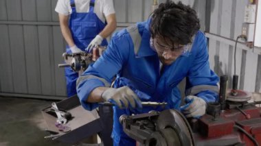 Young man sanding or iron at industrial factory, mechanic working job while polish metal, male having skill built steel with tool, engineer and equipment, labor and steelworks, industry concept.