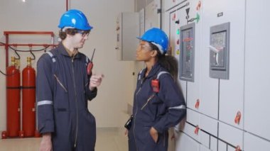 Electrical young woman and man engineer examining maintenance cabinet system electric in the control room at industrial factory, technician or electrician inspection power distribution.