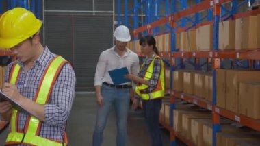 Genç adam ve kadın işçi hisse senedi ve teftişi panoda belgelerle kontrol ederken, yönetici de fabrikadaki depoda şikayet ediyor. Depoda çalışan işçi hatası, lojistik ve kargo..