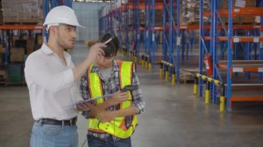 Genç bir kadın müdürle konuşurken fabrikadaki depodaki panoda imzalı belge, patronla raflardaki kargo dağıtımı, nakliye ve lojistik konsept hakkında çalışan tartışması..