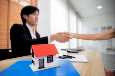 Emlakçı erkek ve müşteri kadın, kredi evi ve sigorta, müşteri ve konut ve iş konseptiyle ilgili yatırım danışmanlığı konusunda anlaşma sağlandıktan sonra el sıkışır..