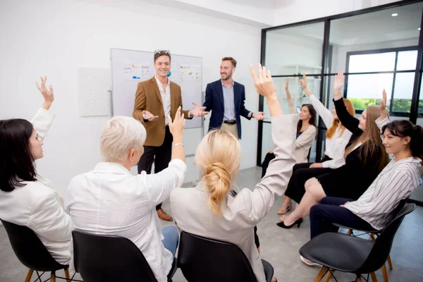 Young caucasian businessman asking opinion and brainstorm of employee while raise hand up for participation together at office, community of business and meeting of leader for presentation project.
