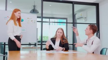 Grup iş adamları finans ve kâr hakkında pazarlama ile buluşurken, iş kadını da planlama ve beyin fırtınası için meslektaşlarıyla birlikte sunum ve grafikleri ve grafikleri beyaz tahtada açıklıyor..