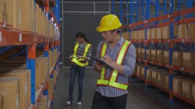 Young man and woman worker check stock and inspection with document on clipboard in the warehouse at factory, worker working at storehouse, logistic and cargo, shipping and distribution.