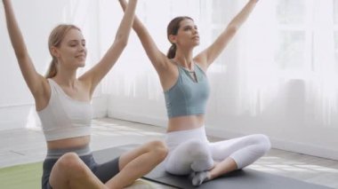 Two young people woman practicing exercise or yoga on mat for balance and breathing together at home, coach training woman workout with flexible of muscle, health care and sport concept.