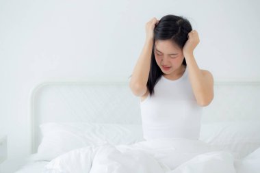 Genç Asyalı kadın yatak odasında yatak odasında baş ağrısı, mutsuz kadın yorgunluğu ve baş ağrısı, endişe ve rahatsızlık, baş dönmesi ve düzensizlik, tıbbi ve sağlık konsepti.