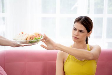 Yemek servisi yapan elleri ve tabela yapan beyaz genç bir kadın obez ile sağlıksız yiyecek olmadığını söylüyor, kadınlar diyet, beslenme ve fast food için baştan çıkarıcı yiyecekleri reddediyor, kötü, sağlık kavramları.
