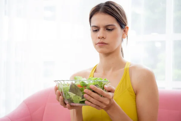 Jovem Caucasiana Sentada Sofá Segurando Salada Legumes Enquanto Sente Repugnante — Fotografia de Stock