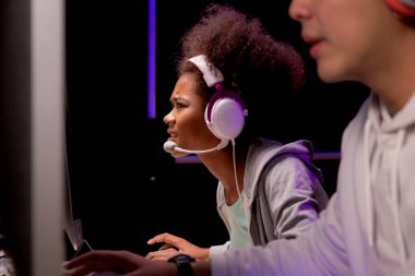Genç Afrikalı Amerikalı kadın ve Asyalı erkek kulaklık takıyor video oyunu oynuyor ve canlı yayında mikrofon, oyun ve esport ile rekabet veya oyuncu seçimi, eğlence konsepti.