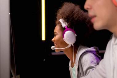 Genç Afrikalı Amerikalı kadın ve Asyalı erkek kulaklık takıyor video oyunu oynuyor ve canlı yayında mikrofon, oyun ve esport ile rekabet veya oyuncu seçimi, eğlence konsepti.