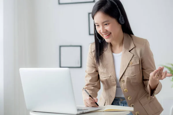 自宅やビデオ通話会議からの作業のためのラップトップコンピュータを使用して若いアジアの女性オンラインと自宅でノートに書き込みます 女性の会議遠いとサービス担当者 ビジネスコンセプト — ストック写真