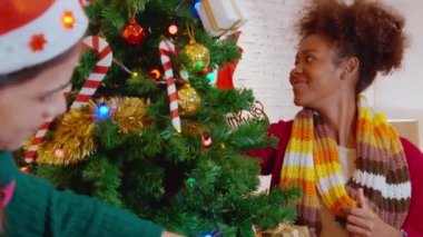 Mutlu genç kadın ve arkadaşlar Noel ağacını süslüyor ve süslüyor evde eğleniyor, kadın ve erkek dekorasyon festivali xmas ile heyecanlı, Noel ve yeni yıl ya da tatil konsepti.