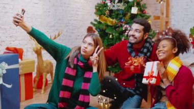 Genç arkadaşlar, Noel arifesinde, Noel arifesinde, Noel arifesinde, bayramında veya tatil konseptinde sosyal medyayı kullanan kadın ve erkek, heyecanlı ve akıllı telefonlardan keyif alarak görüntülü arama yaparlar..