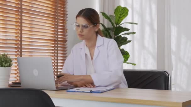 Young Woman Doctor Working While Looking Document Clipboard Using Laptop — Video Stock