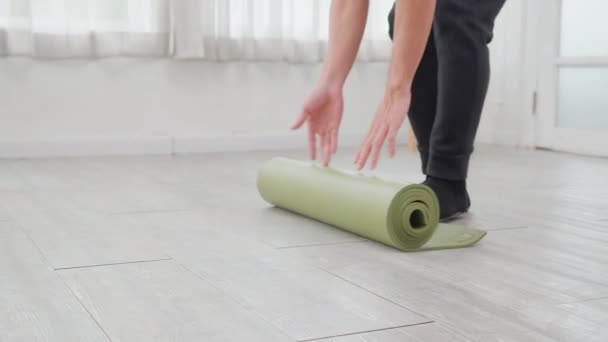 年轻的亚洲男子手拿着脚垫瑜伽在地板上打滚 准备冥想 在家里做文娱活动 进行锻炼 练习瑜伽 锻炼活动和业余爱好 促进健康 — 图库视频影像
