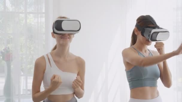 两名年轻的高加索女人头戴Vr耳机 在客厅一起锻炼和锻炼 未来主义和虚拟现实的创新五花八门 女性玩着游戏和打拳享受着 — 图库视频影像