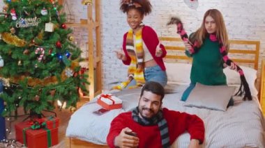 Genç arkadaşlar, Noel arifesinde, Noel arifesinde, Noel arifesinde, bayramında veya tatil konseptinde sosyal medyayı kullanan kadın ve erkek, heyecanlı ve akıllı telefonlardan keyif alarak görüntülü arama yaparlar..
